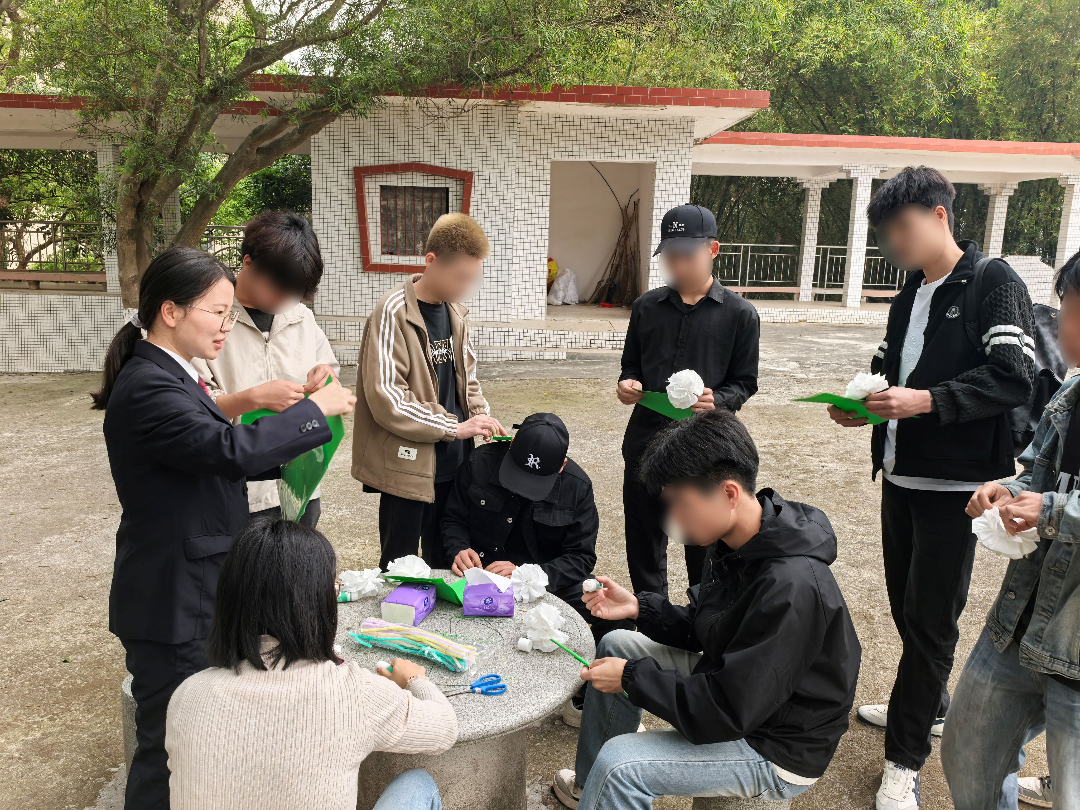 2025年4月8日检察干警与司法社工带领罪错未成年人围坐在陵园广场，用彩纸、餐巾纸、铁丝等材料制作手工白菊111.jpg