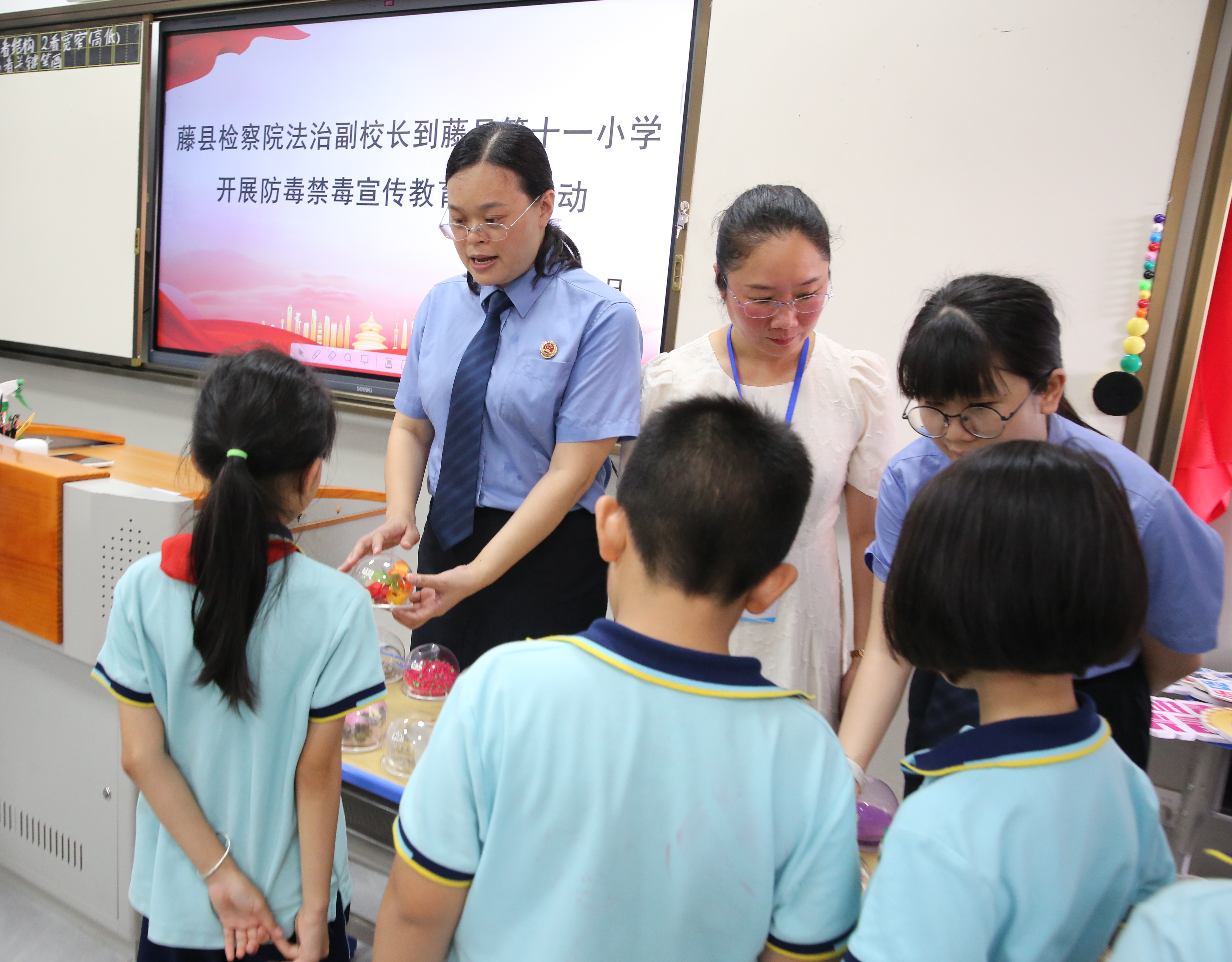 黄洁华拿起一个个逼真的模具，细致地为同学们讲解各类毒品的特征与伪装伎俩.JPG