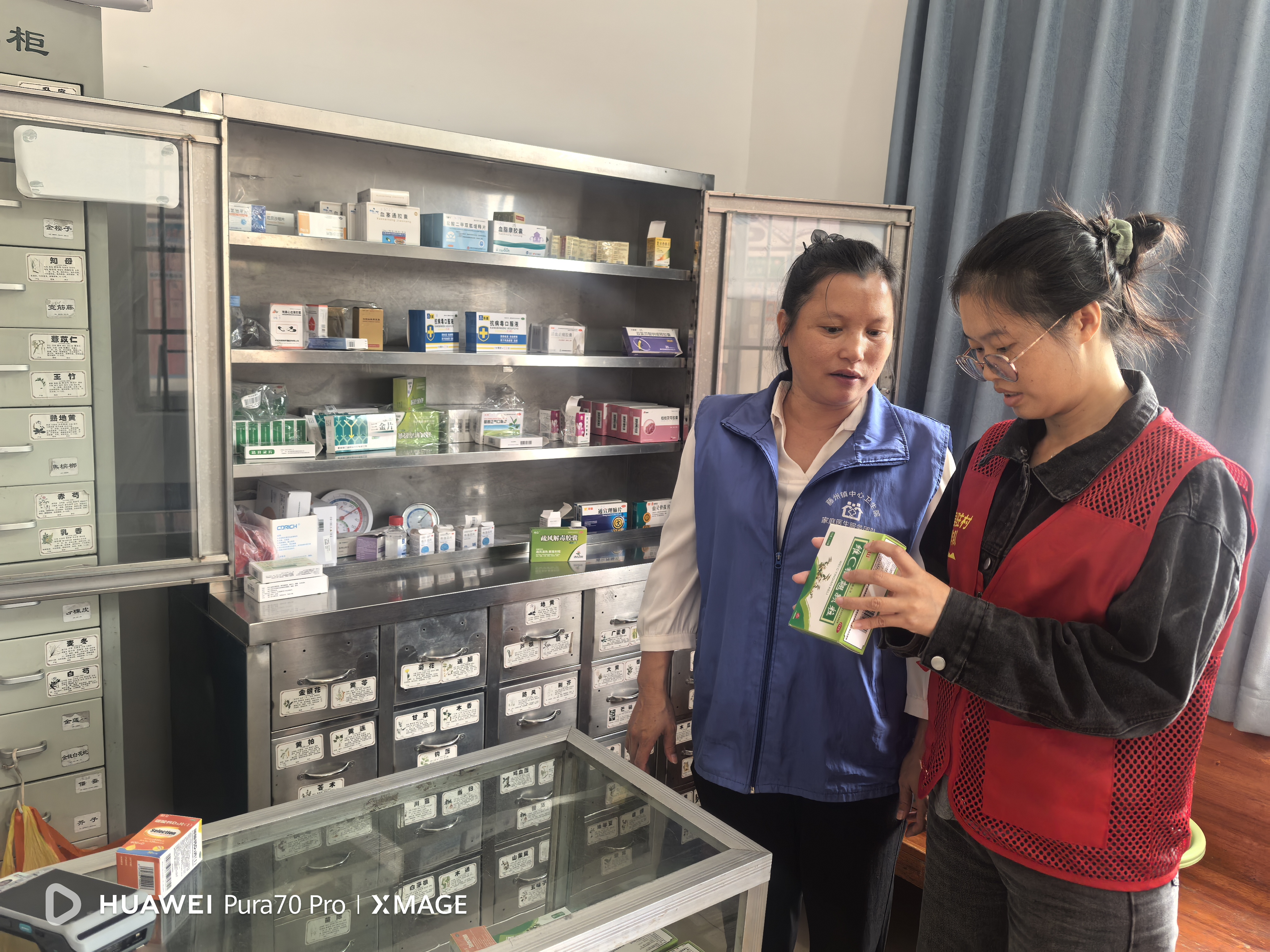 药房内,黄丽华与欧建兴认真询问接诊量及药品消耗情况,重点查看药品外观问题、生产日期与效期,确保用药安全。.jpg